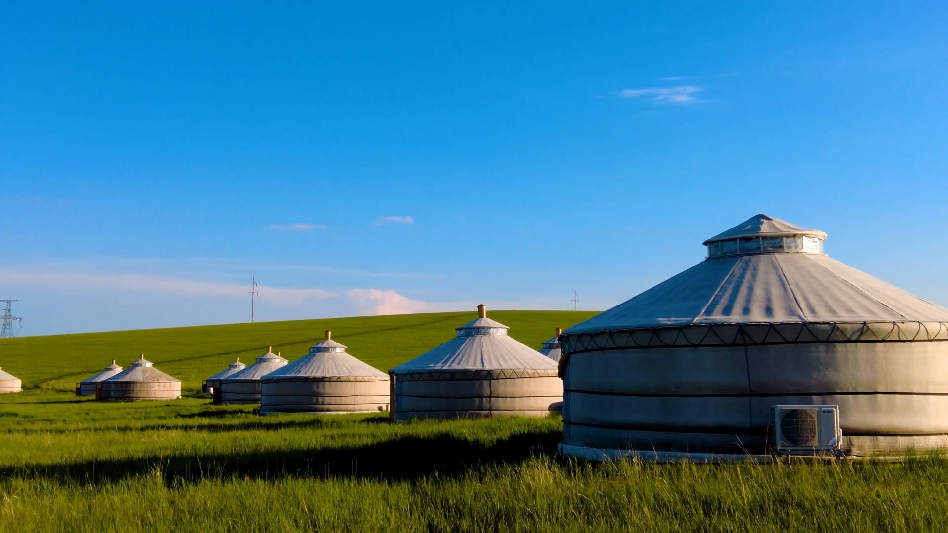 实拍蓝天白云下碧绿的草原上散落的蒙古包群