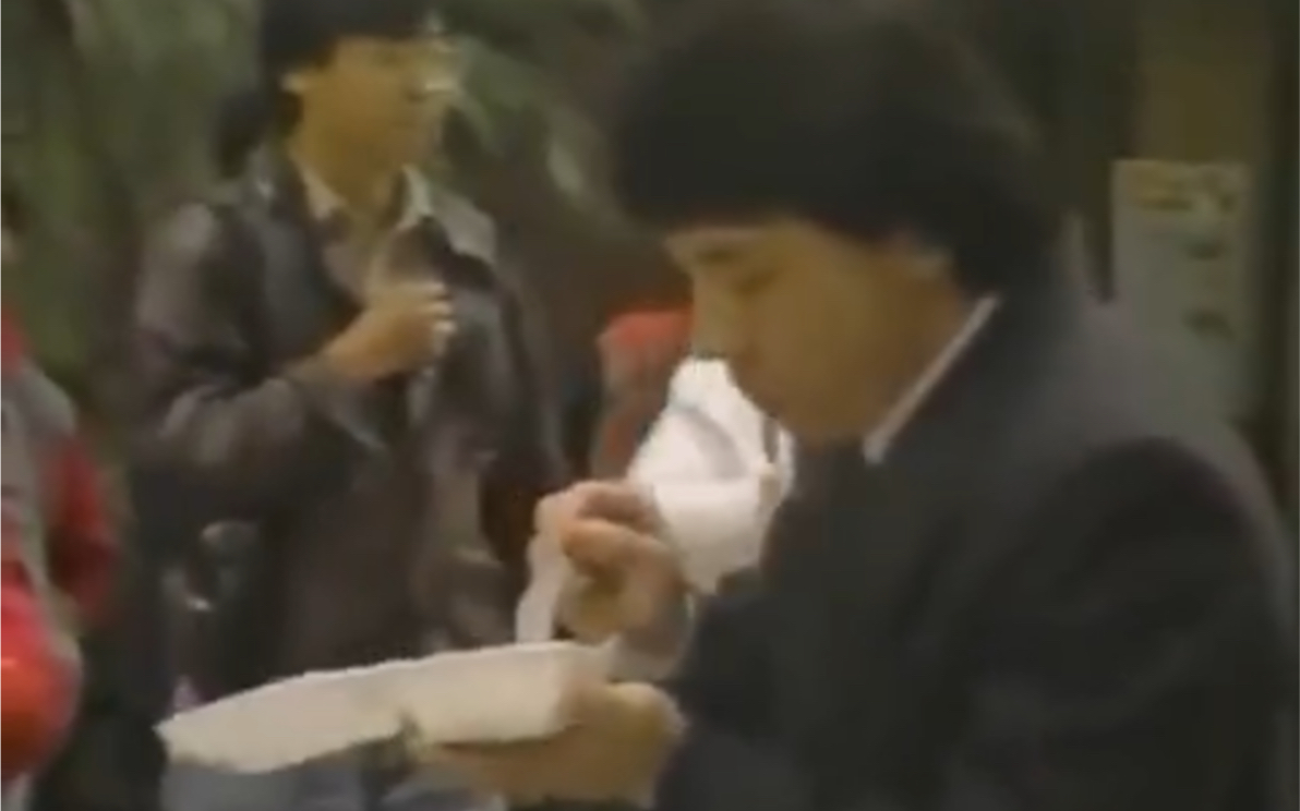 1987年成龙在片场吃盒饭的真实影像，因盒饭太过好吃，还被洪金宝蹭了一大口