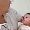 爸爸怀抱着出生20多天的女儿，宝宝也眨着大眼睛满是好奇