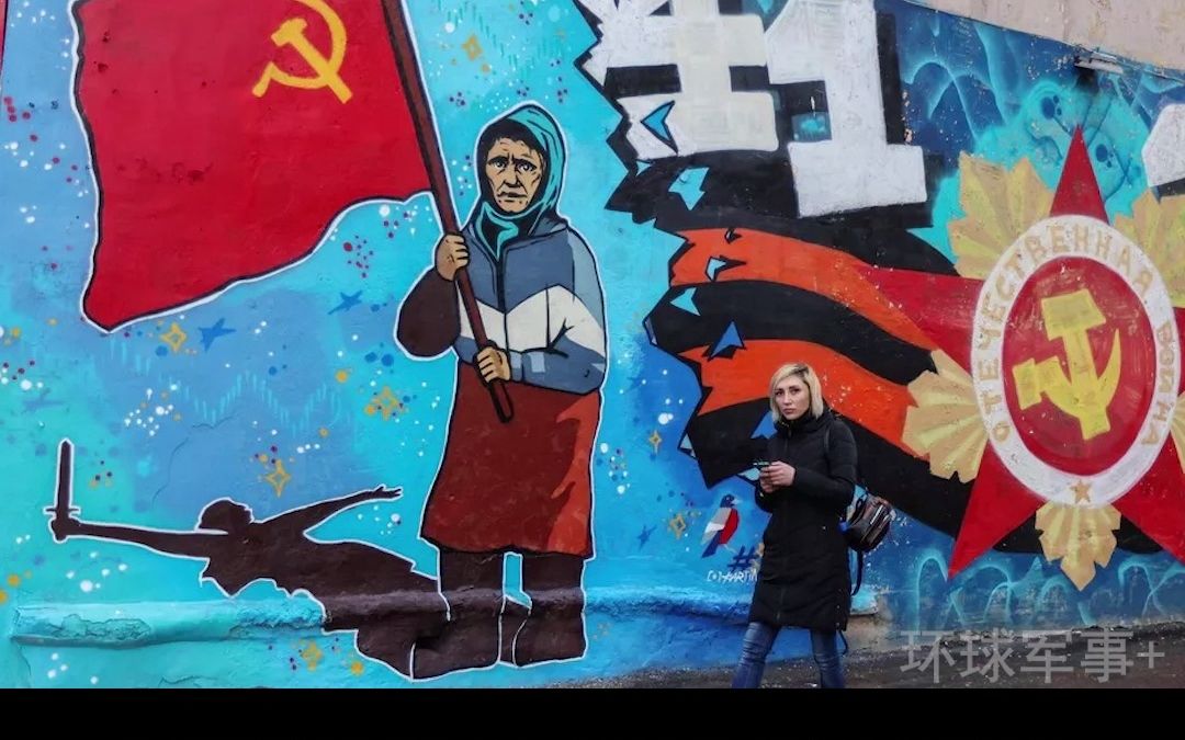 举苏联红旗的乌克兰老奶奶被LPR士兵做成臂章纪念，漫画横幅悬挂整墙