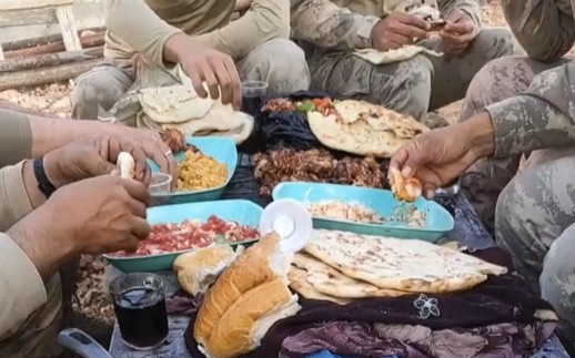 土耳其军队在野外吃午餐，有面包、大饼、烤肉、番茄青椒和碳酸饮料