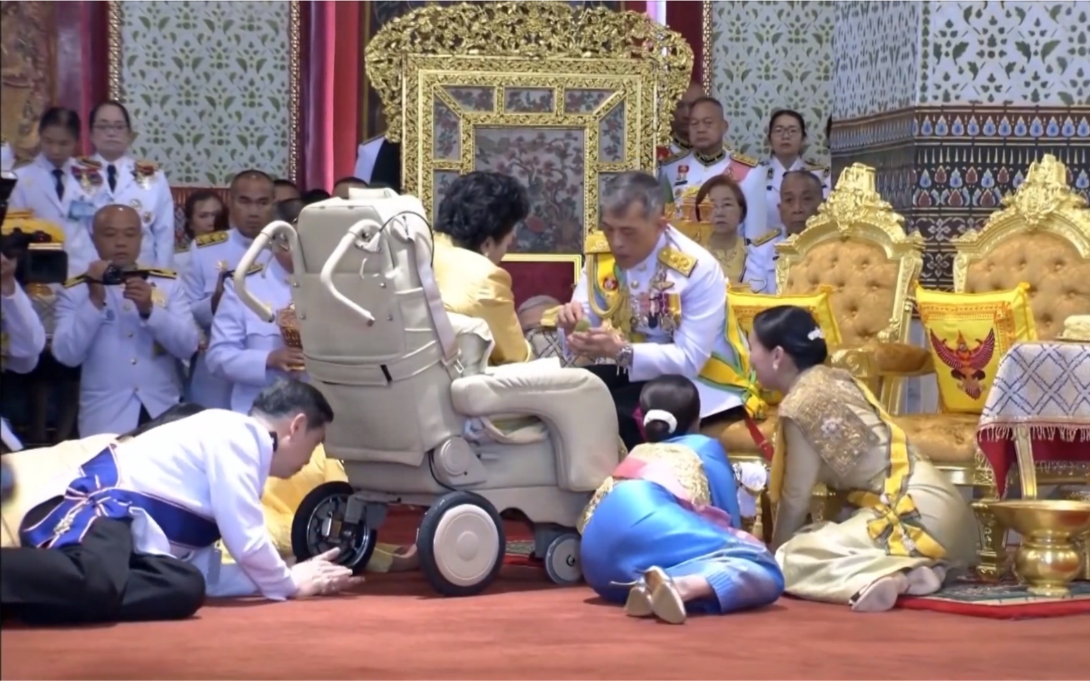 坐在轮椅上的原配妻子接受泰王接见，苏提达王后立即起身跪下行礼