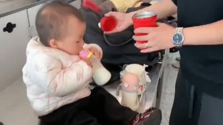 年轻爸妈带宝宝出门.牛奶带多了无法带上飞机.宝宝在机场安检处喝掉。