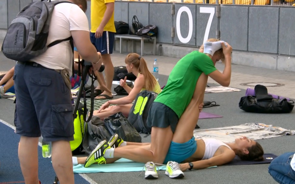 田径场教练为运动员做拉伸运动