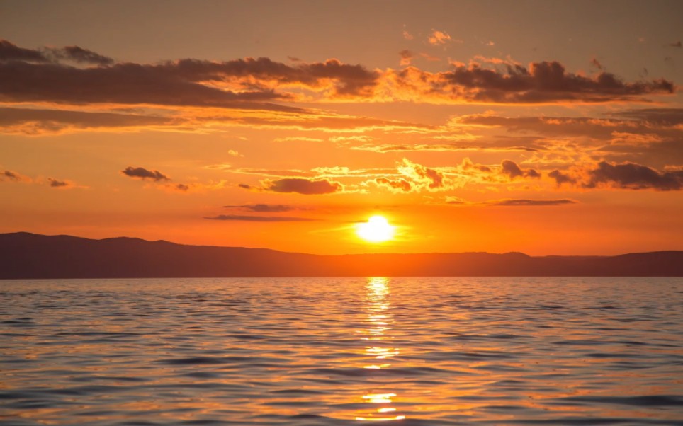小城夏天橘黄色的日落吞没在海平线