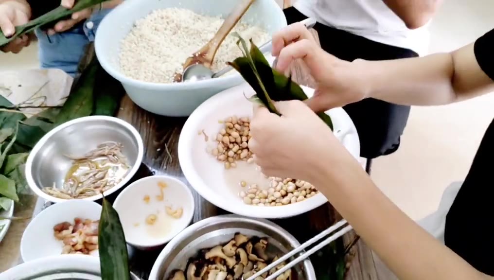 一群人来自不同的镇都是第一次包粽子,包法各有不同,你认得哪种