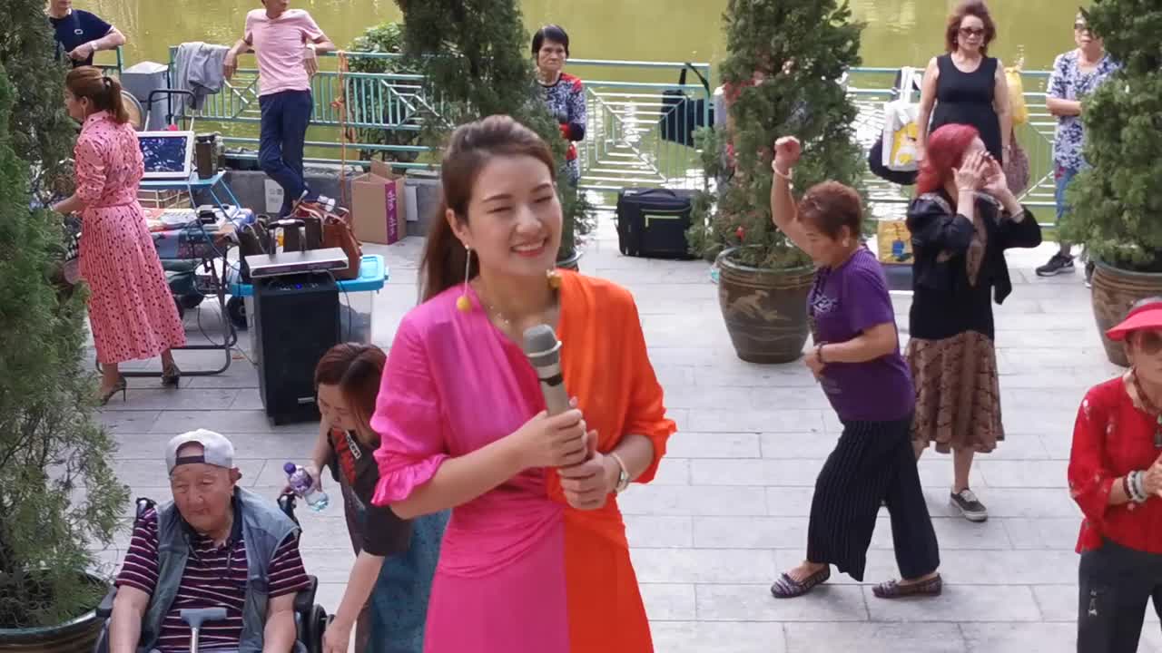 [图]美女艺人妙妙街头演唱情歌《爱你爱在心坎里》歌声动听，众人围观