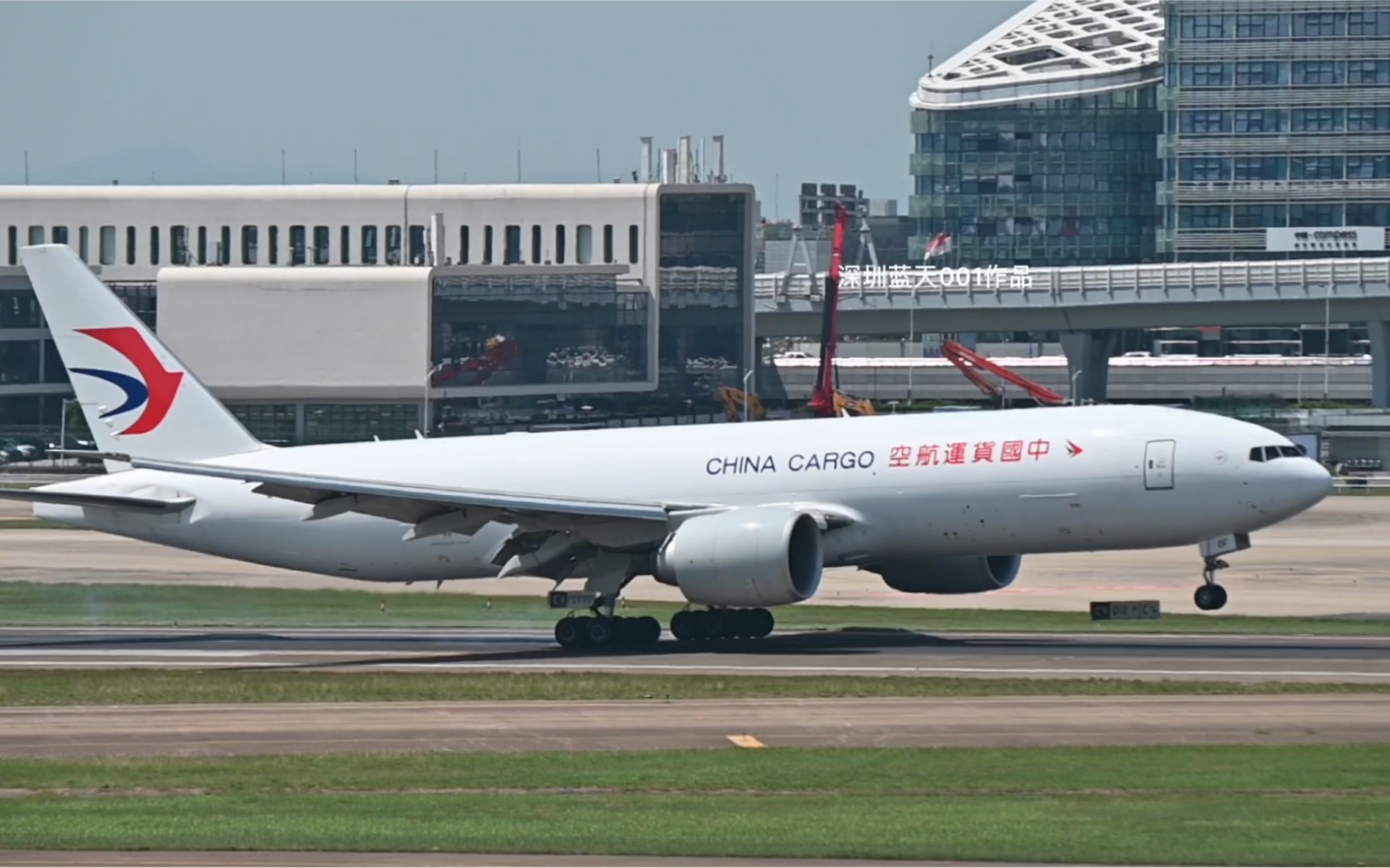 新涂装中货航777f在一跑33头降落后缓缓滑行至货机群.