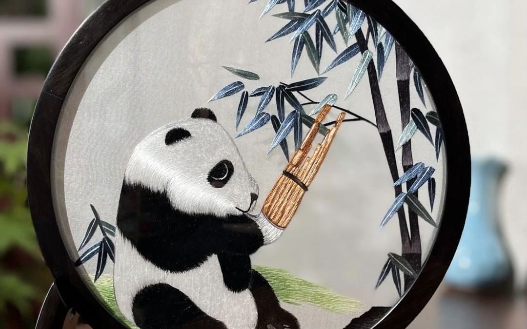 纯手工双面绣熊猫,卧于竹林下,摆弄乐器,好不惬意,精工细作,纤毫可鉴