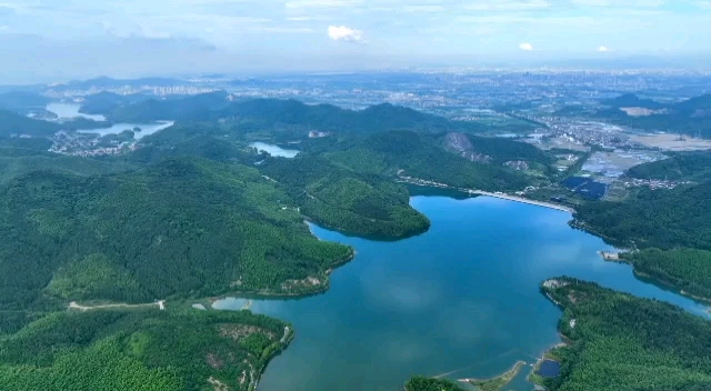 [图]航拍下的镇海九龙湖秦山村水库一带，湖水映着山色，松林掩着水波，映衬着水域宽阔而壮观，蓝天白云下，这里景色秀丽、环境幽静，俨然一幅山清水秀的“生态美景图”。