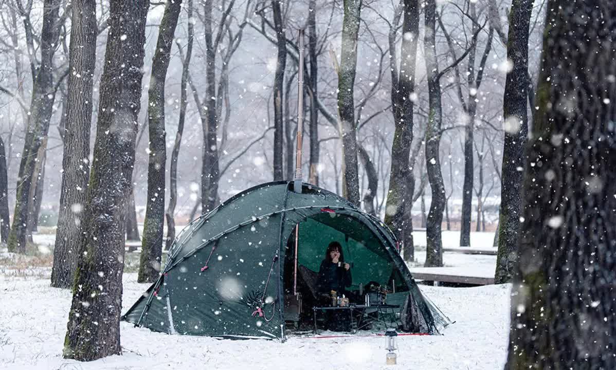 雪地里独自露营 太冷了,雨变成了雪. 独自在炎热的帐篷里放松露营