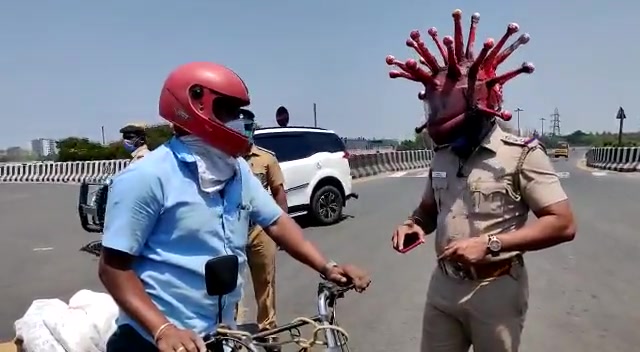 印度阿sir戴着形状似冠状病毒的头盔提醒往来的驾驶员在疫情大流行